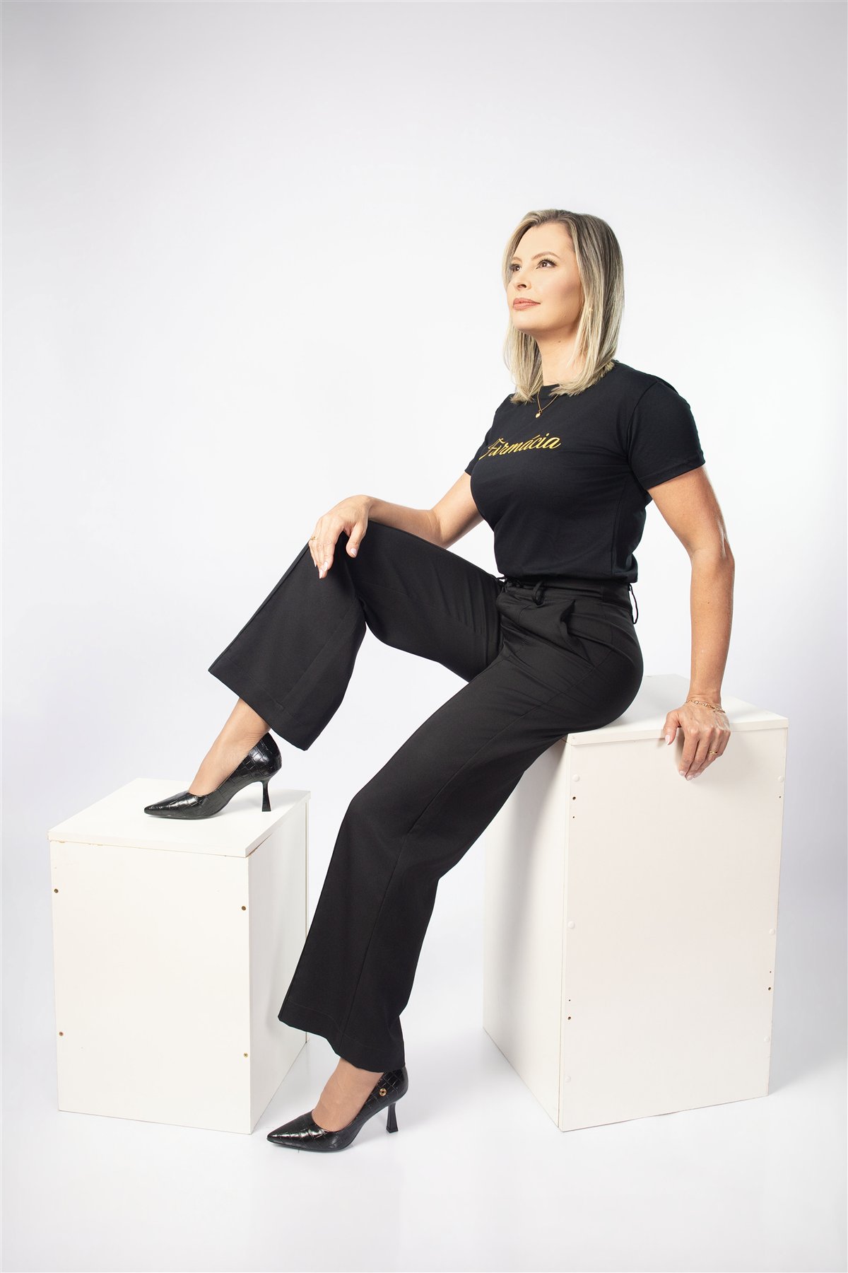Eliana sentada em cubos durante o ensaio com camisa personalizada
