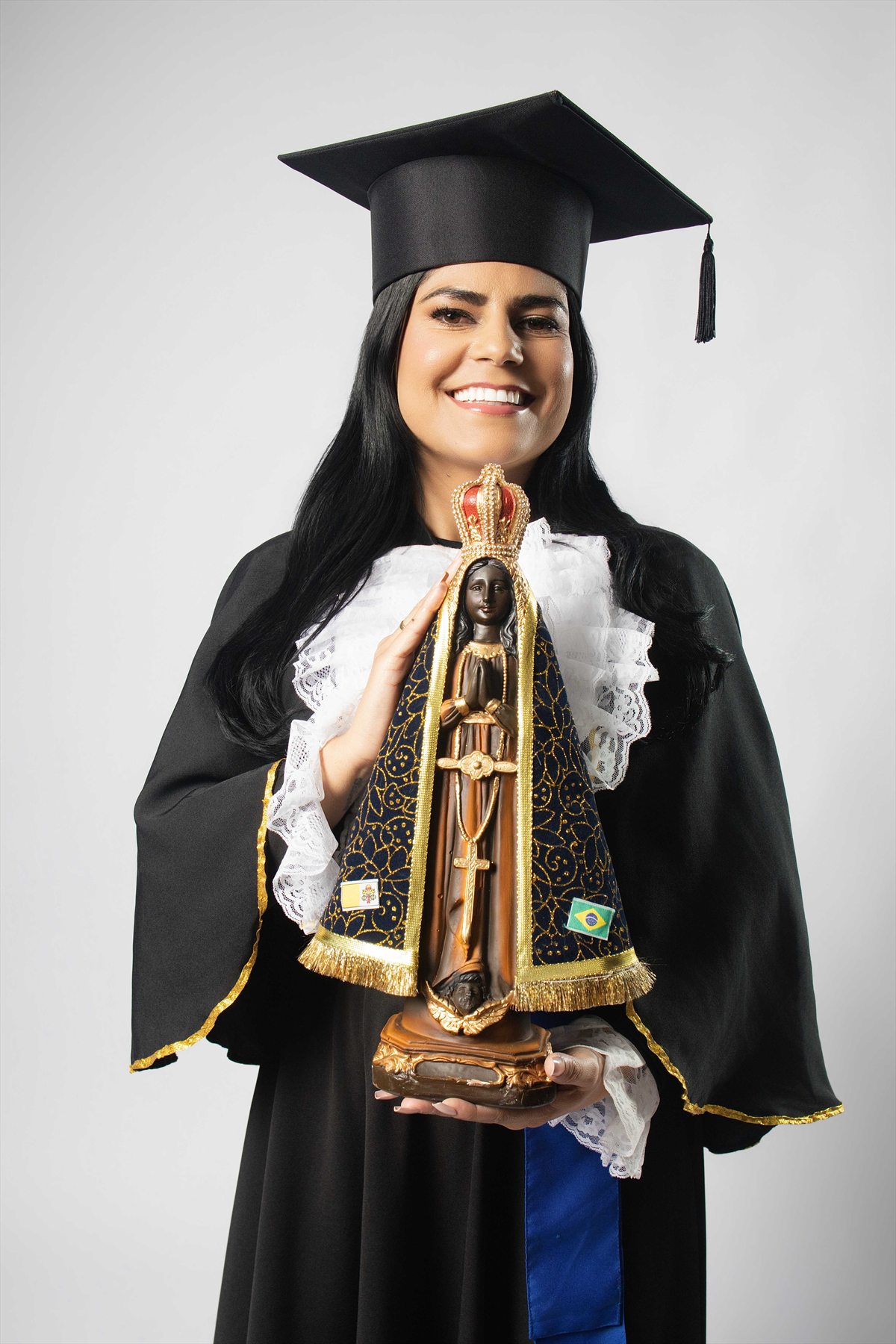 Formanda de beca segurando imagem de Nossa Senhora Aparecida