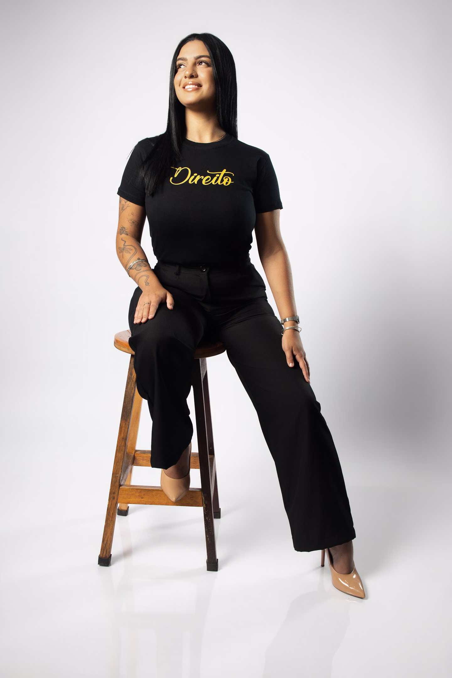 Kailany com a camisa de Direito, sentada em banqueta de madeira durante o ensaio de formatura em Belo Horizonte.