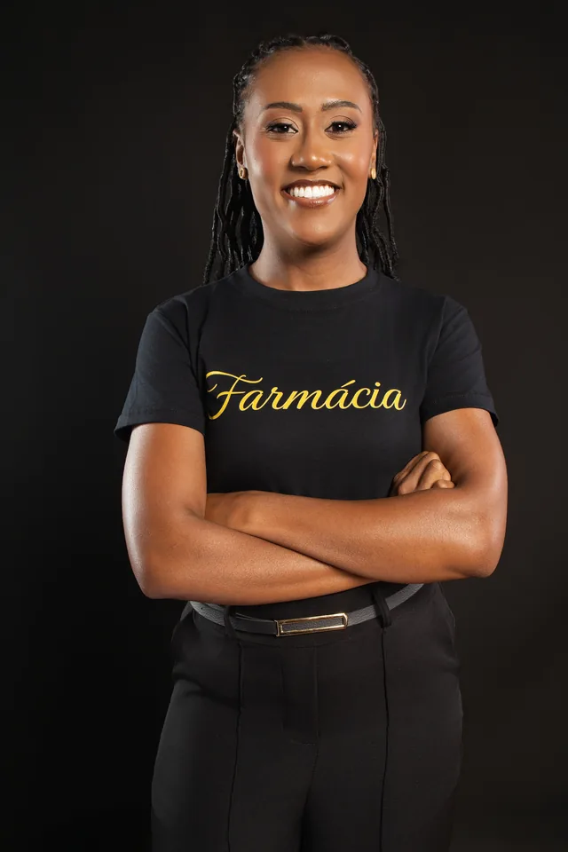 Rebeca com a camisa de Farmácia em um retrato com fundo escuro no estúdio