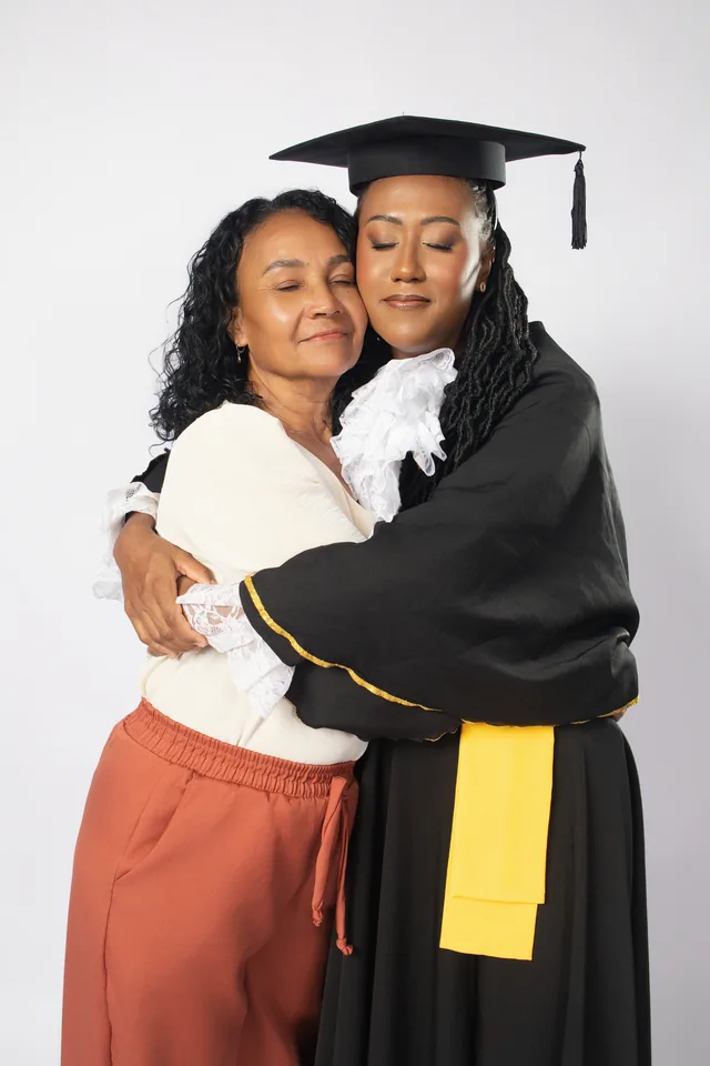 Rebeca de beca em um abraço com uma familiar no ensaio de formatura de Farmácia.