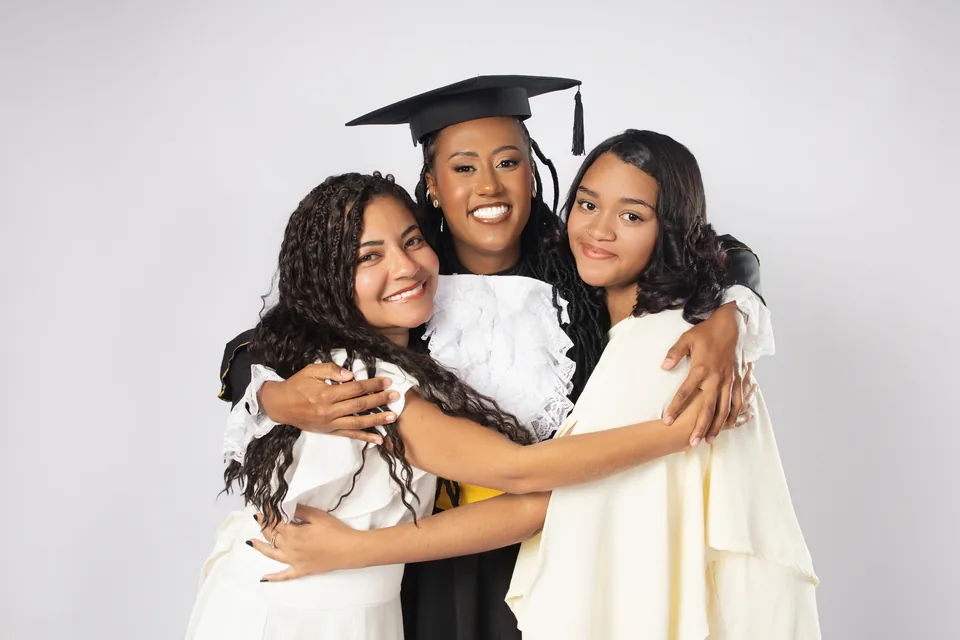 Rebeca de beca abraçada a duas acompanhantes em uma foto espontânea do ensaio de formatura