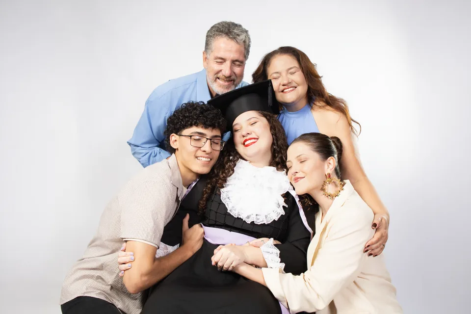 Bruna de beca abraçada com sua família no ensaio de formatura de Letras.