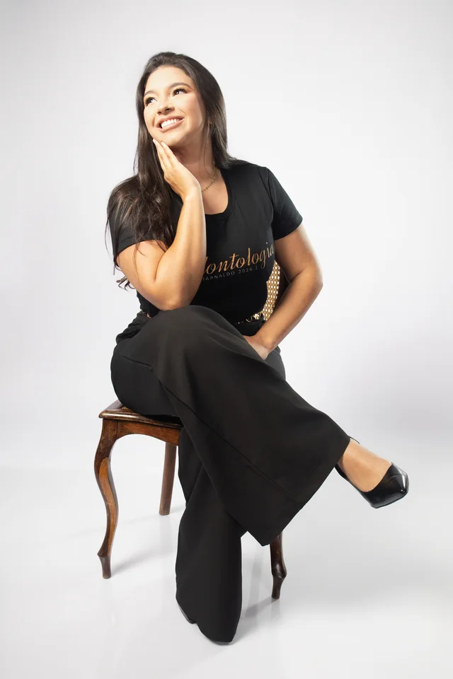Ysabella sentada em uma cadeira clássica com a camisa de Odontologia no ensaio de formatura em Belo Horizonte