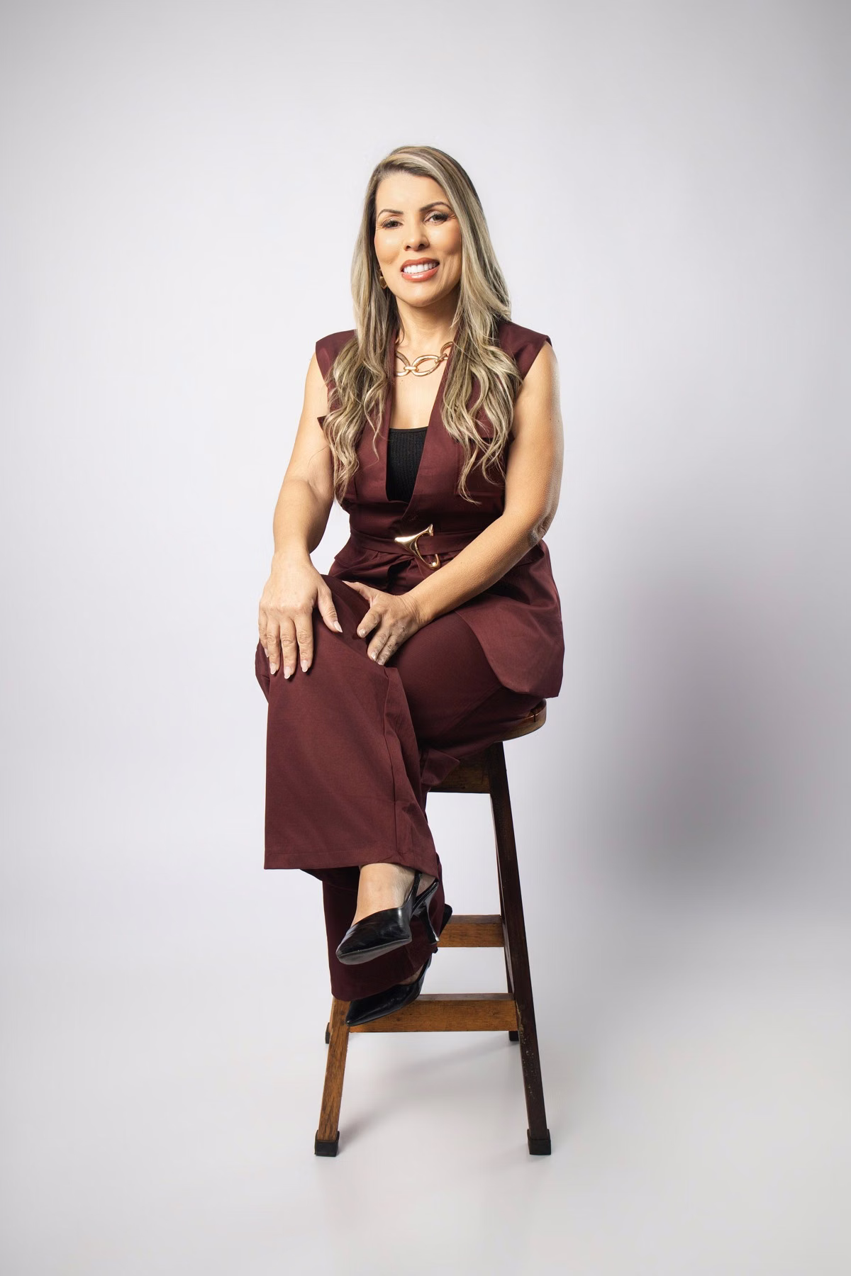 Retrato produzido no estúdio: empreendedora sentada, vestindo um conjunto vinho