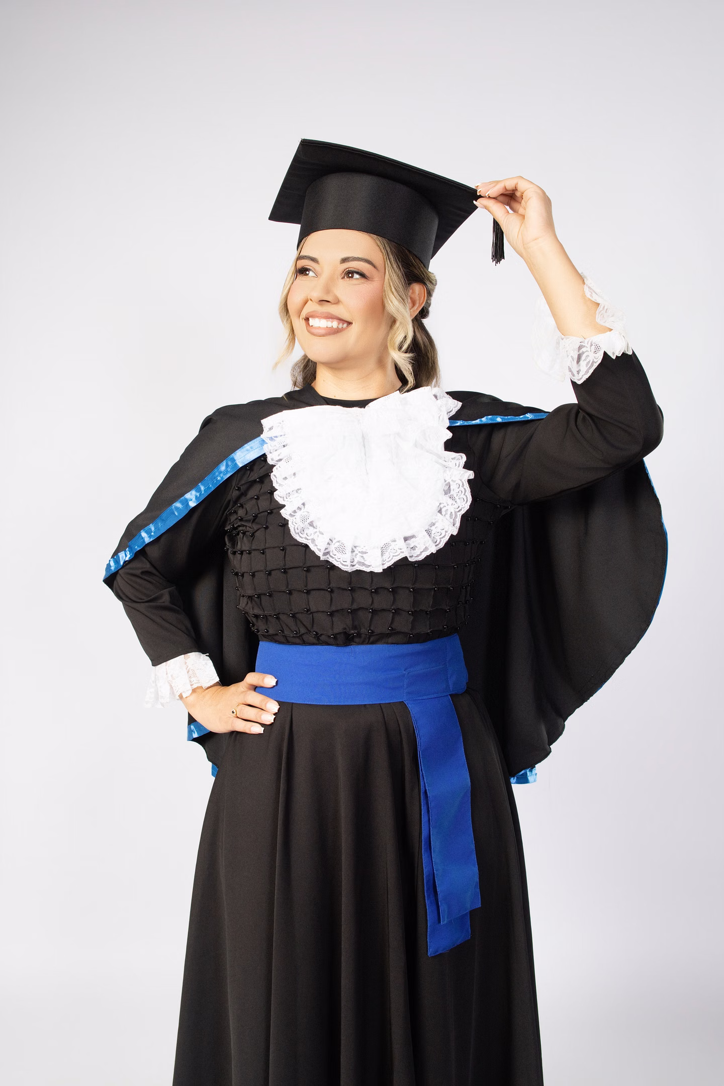 Aline de beca azul, em pé, segurando o capelo no ensaio de formatura em Belo Horizonte