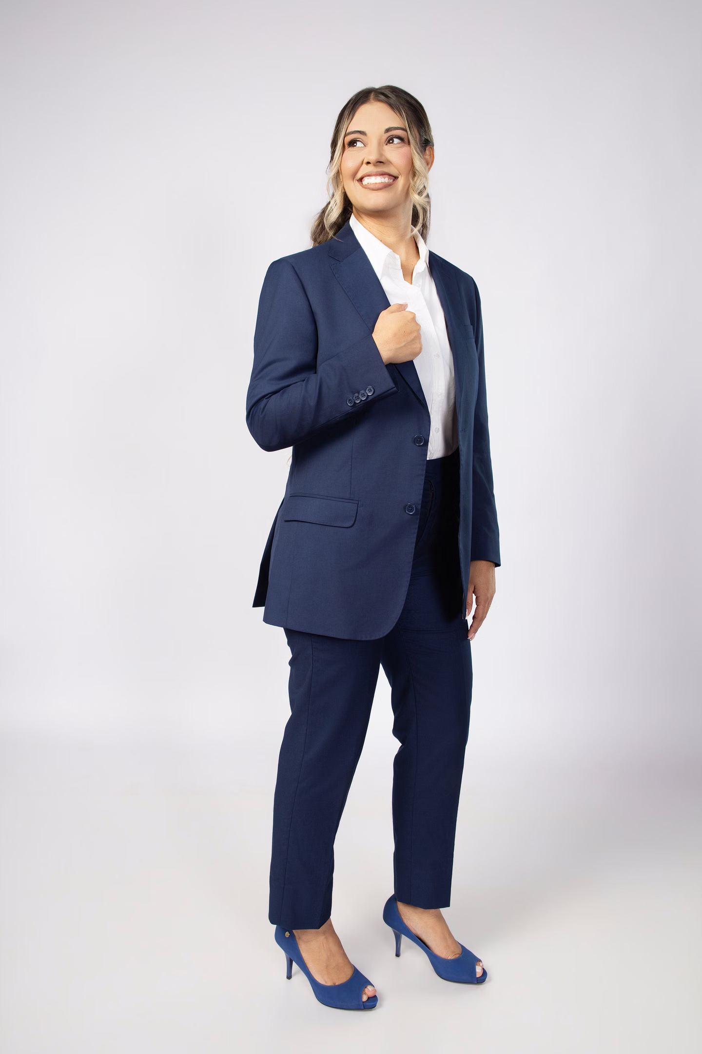 Aline em pé com blazer azul sobre fundo claro no ensaio de formatura em Belo Horizonte