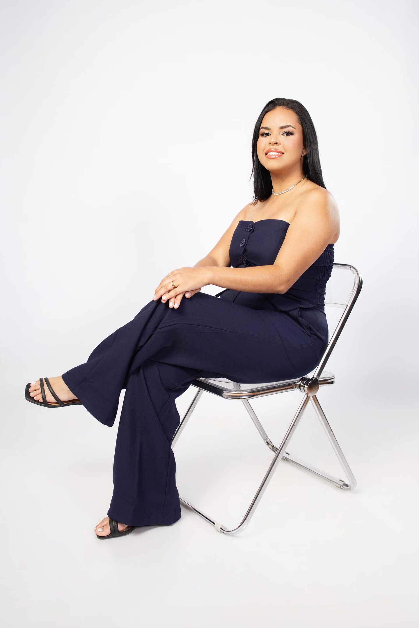 Jully sentada com roupa azul em uma cadeira transparente no ensaio de formatura em Belo Horizonte