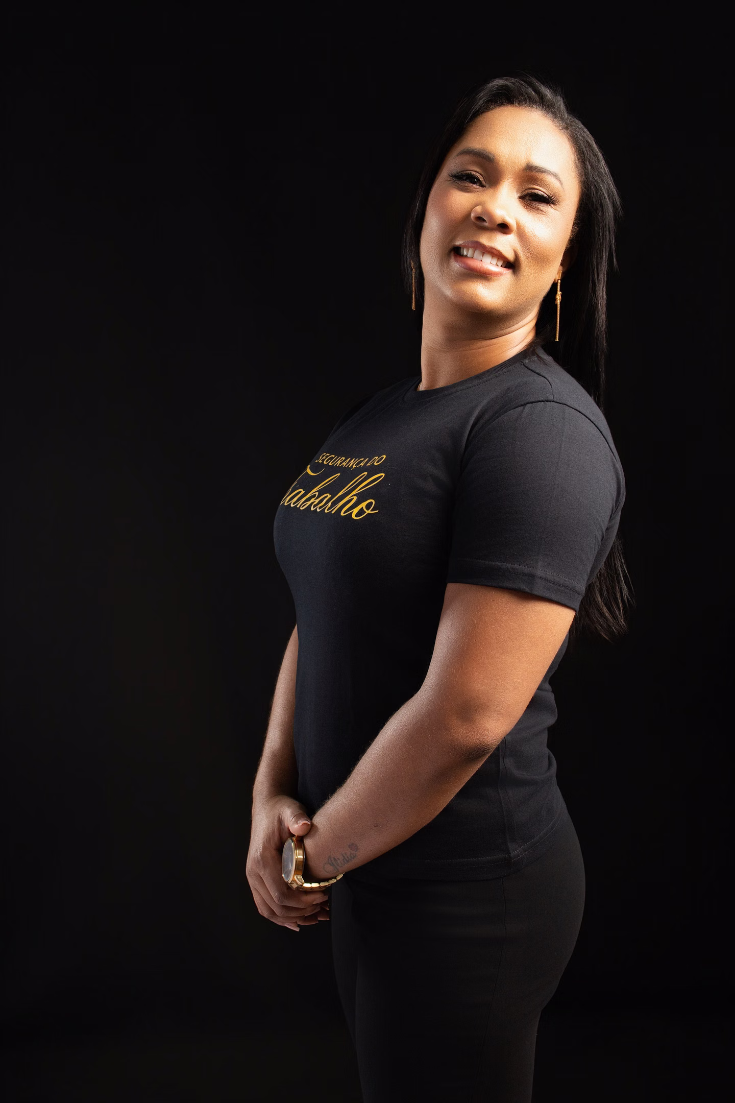 Lilian sorrindo com a camisa de Segurança do Trabalho sobre fundo escuro no ensaio de formatura em Belo Horizonte