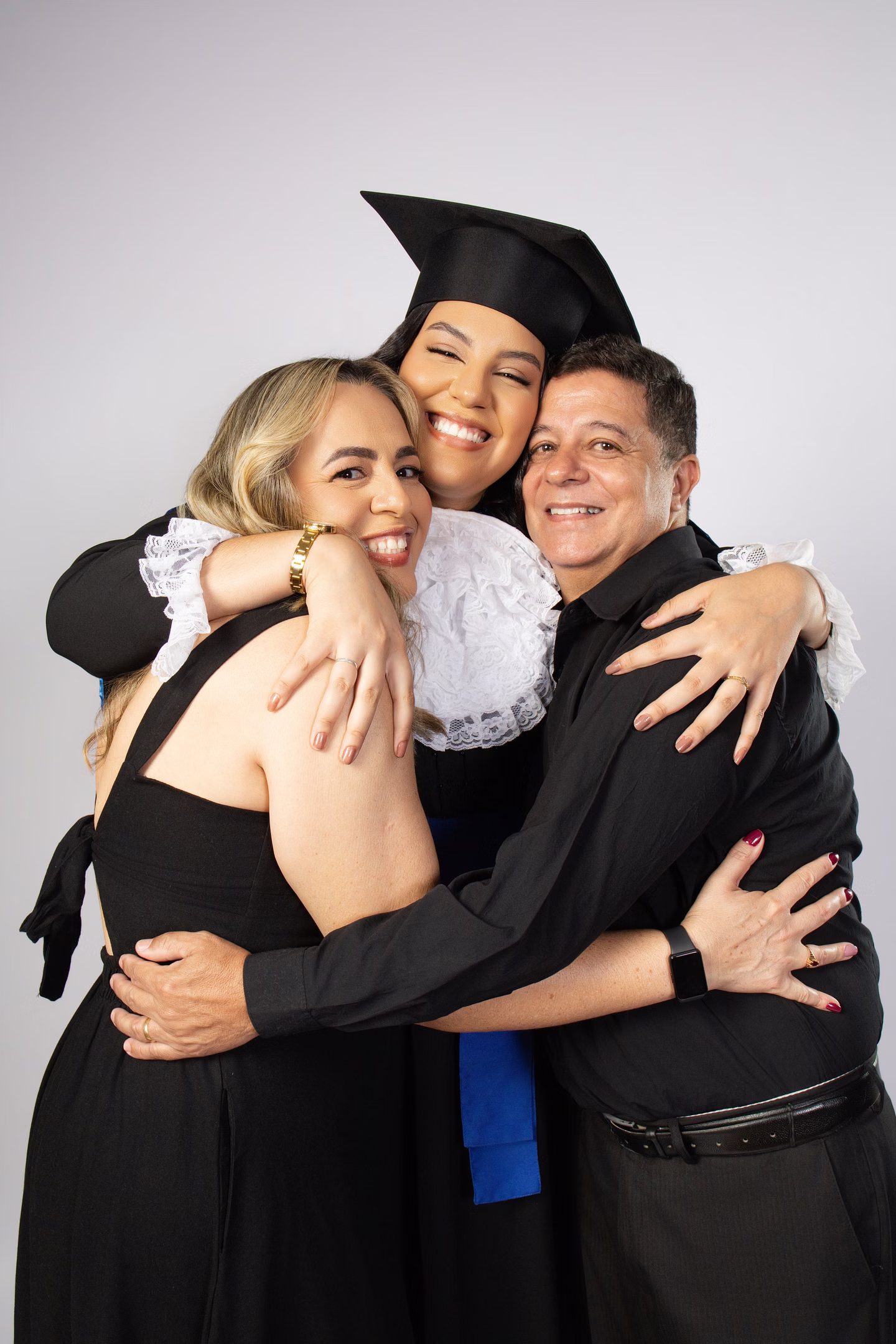 Samara de beca em um abraço com duas pessoas no ensaio de formatura em Belo Horizonte