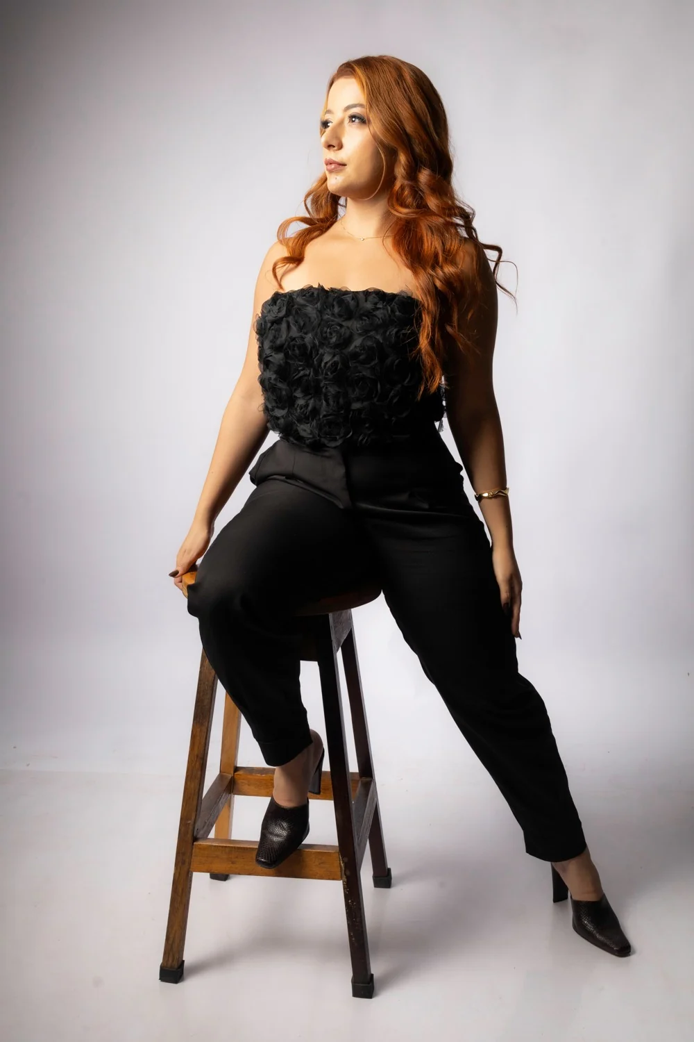 Brenda Rocha em retrato com roupa preta e banqueta