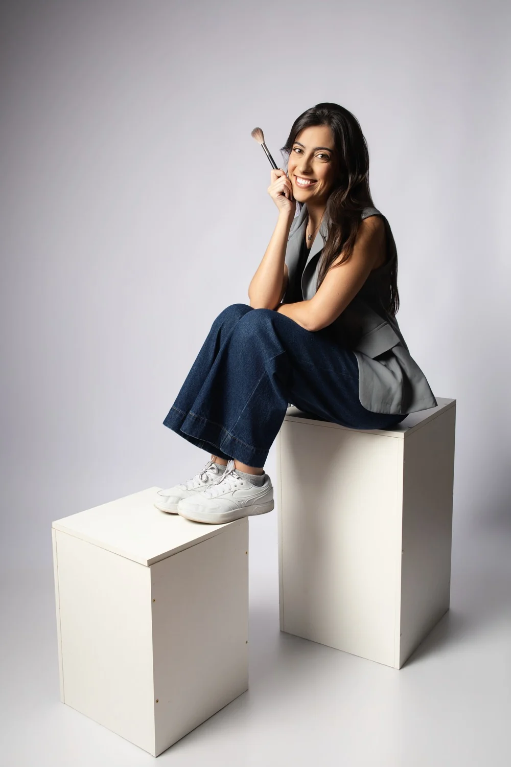 Odara sentada em cubos, com pincel de maquiagem